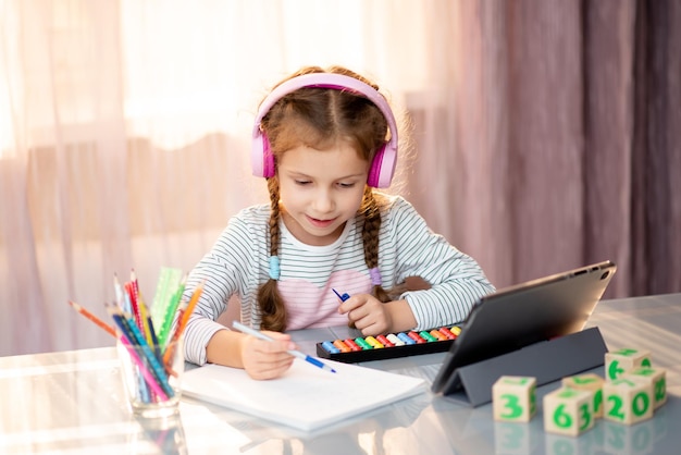 Uma menina do ensino fundamental aprende aritmética mental online em casa. Educação.