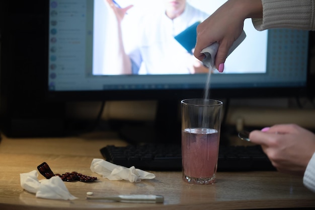 Uma menina doente se senta na frente de um computador, ela tem uma consulta online com um médico que o médico é