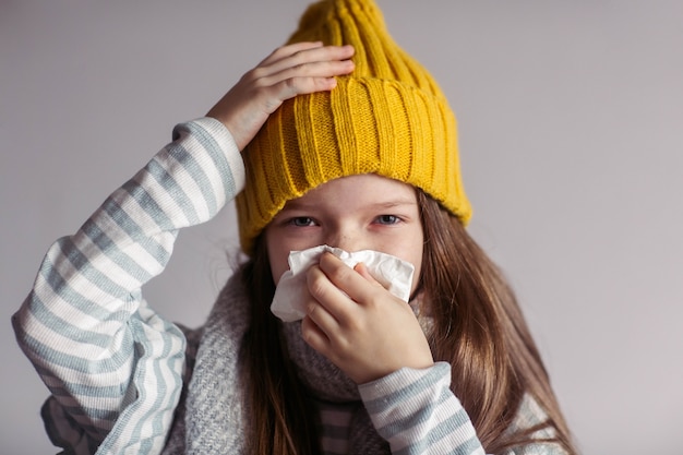 Foto uma menina doente tem uma doença viral, uma criança doente assoa o nariz