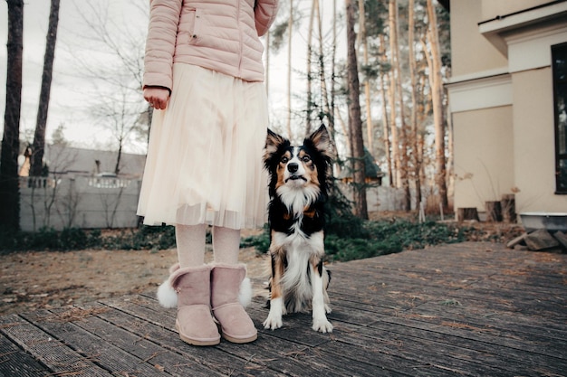 Uma menina e seu cachorro em pé em um deck de madeira.