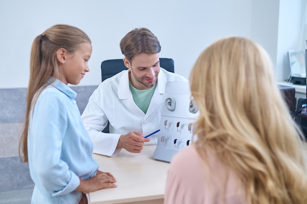 Uma menina e sua mãe observando uma diversidade de aparelhos auditivos oferecidos por um médico qualificado