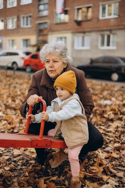 uma menina e sua velha avó estão brincando no quintal da casa no outono