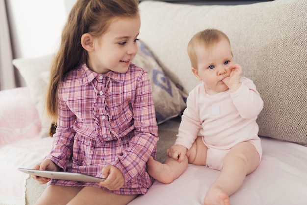 Uma menina e um bebê estão sentados no sofá