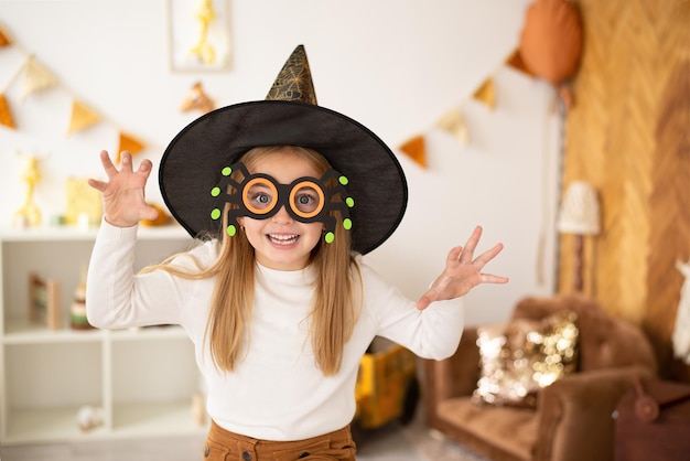 Uma menina em fantasias de bruxa está fazendo brincadeiras no halloween