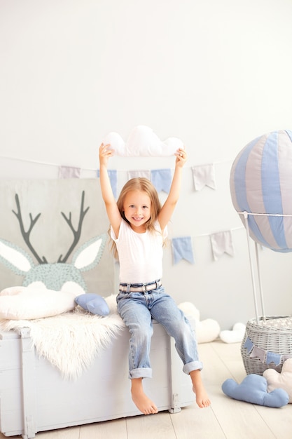 Uma menina em roupas casuais mantém uma almofada de nuvens contra a parede de um balão decorativo. A criança brinca no quarto das crianças. O conceito de infância. aniversário decorações