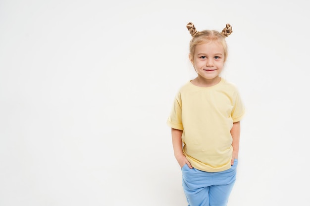 Uma menina em um fundo claro em uma camiseta amarela e calça azul criança feliz em um fundo brilhante.