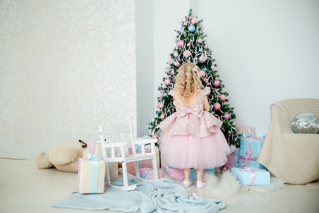 Uma menina em um vestido que decora a árvore de Natal.