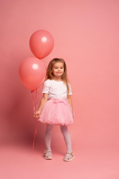 Uma menina em um vestido rosa com balões rosa em um fundo rosa