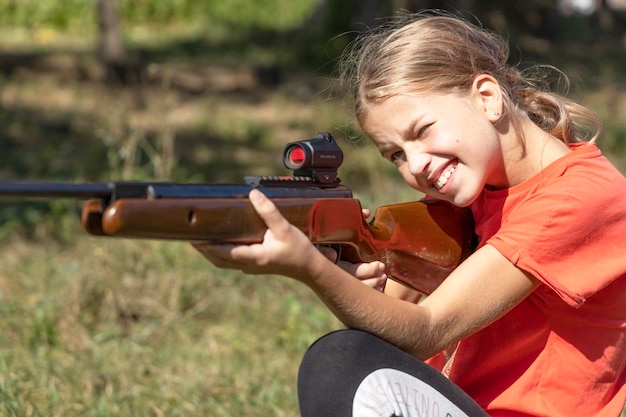 Uma menina em uma caça aponta uma arma.