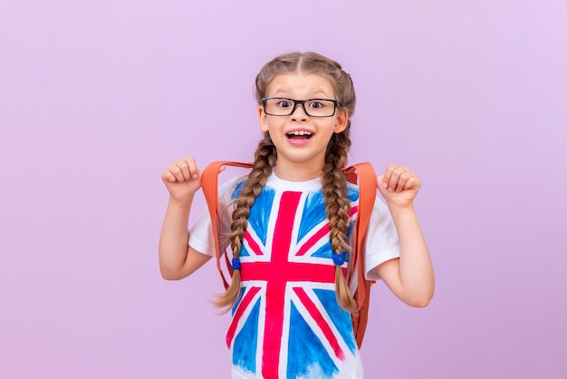 Uma menina em uma camiseta com uma imagem da bandeira inglesa em um fundo roxo isolado. Aprendendo idiomas extrangeiros.