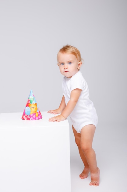 uma menina em uma roupa branca comemora seu aniversário em um fundo branco