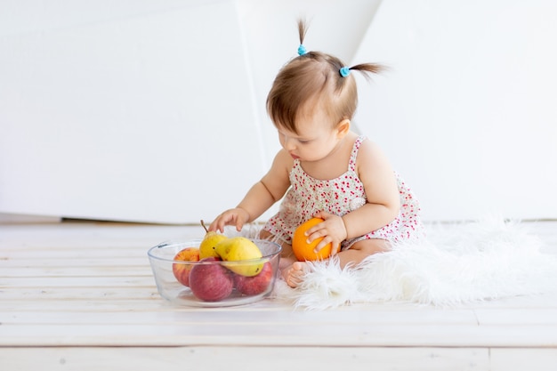 Uma menina em uma sala iluminada sentada com um prato de frutas