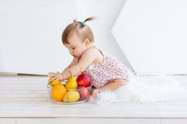 Uma menina em uma sala iluminada sentada com um prato de frutas