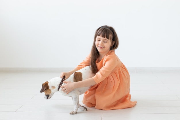 Uma menina encantadora com cabelo escuro em um vestido longo está sentada ao lado do cão jack russell terrier