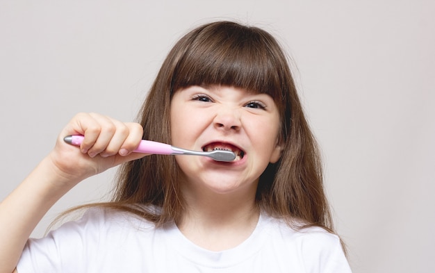 Uma menina escovando os dentes com uma escova de dentes colorida