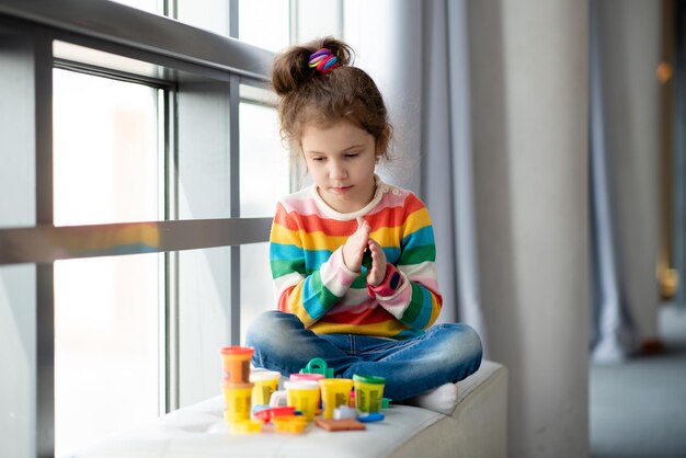 Uma menina esculpe de plasticina