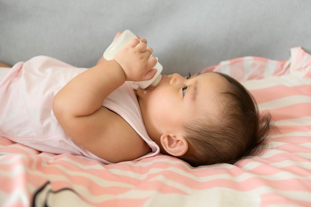 Uma menina está bebendo garrafa de leite família criança infância e conceito de paternidade