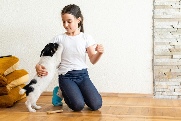 Uma menina está brincando e está treinando um cachorrinho. o cachorro lhe dá uma pata.