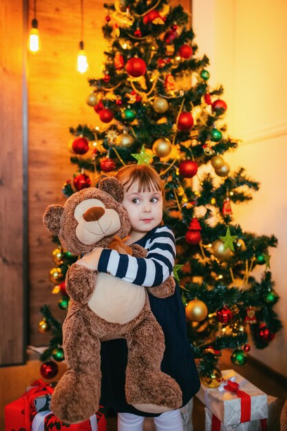 Uma menina está curtindo seu novo ursinho de pelúcia dado pelo Papai Noel na decoração de Natal