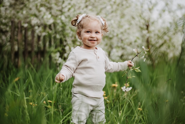 Uma menina está de pé na grama. uma criança em um jardim florido. uma menina com um sorriso.