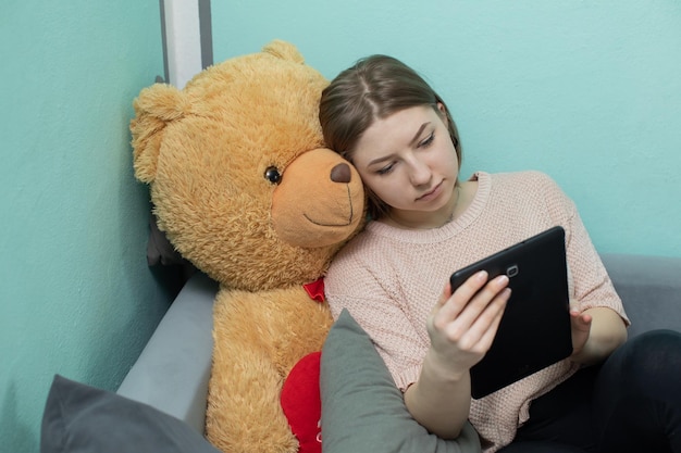 Uma menina está estudando para o exame junto com um grande ursinho de pelúcia