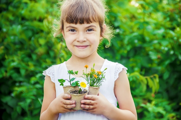 Uma menina está plantando flores. O jovem jardineiro. Foco seletivo.