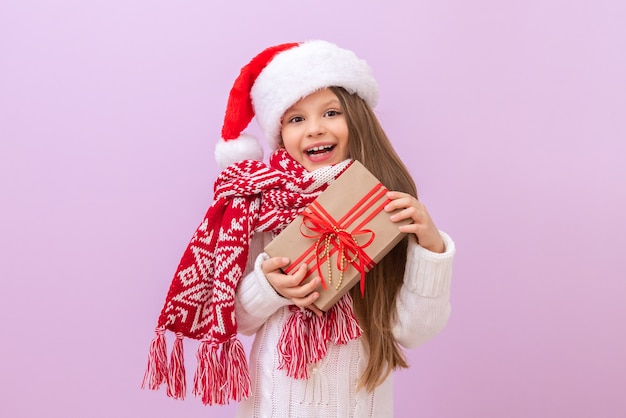 Uma menina está segurando seu presente de Natal e está muito feliz com o feriado. Fundo isolado.