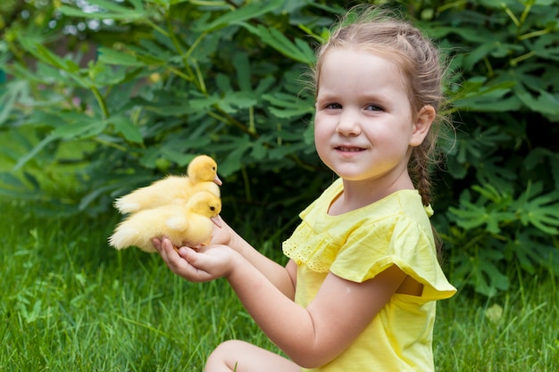 Uma menina está segurando um patinho nas mãos dela. Natureza. Pequeno agricultor. Dia ensolarado de verão