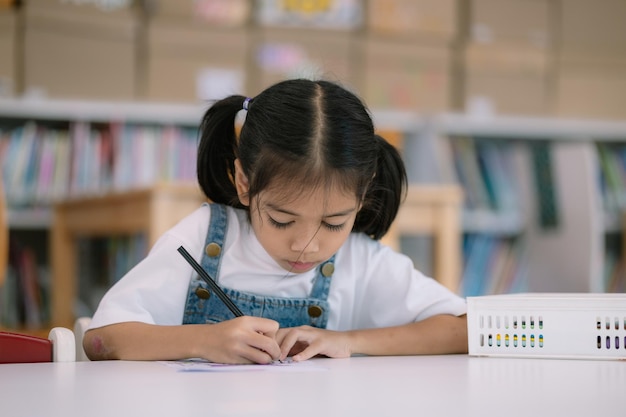 Uma menina está sentada em uma mesa com um lápis e um pedaço de papel
