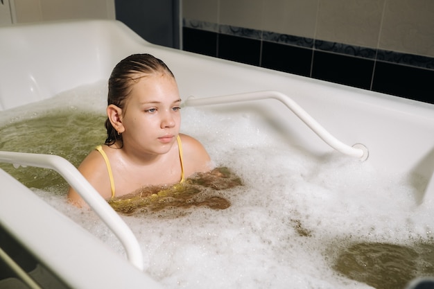 Uma menina faz o procedimento em um banho mineral. O paciente recebe tratamentos de água com banho mineral de pérolas