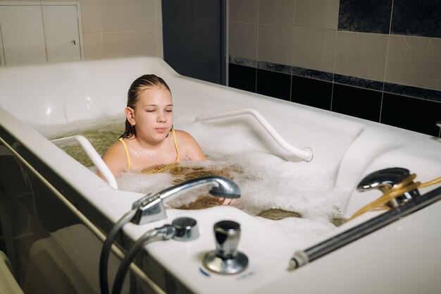 Uma menina faz o procedimento em um banho mineral. O paciente recebe tratamentos de água com banho mineral de pérolas.
