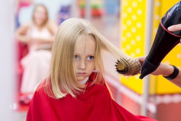 Uma menina faz um corte de cabelo no cabeleireiro.