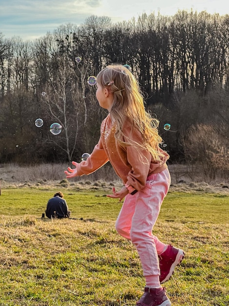 Foto uma menina feliz a correr pelo campo.