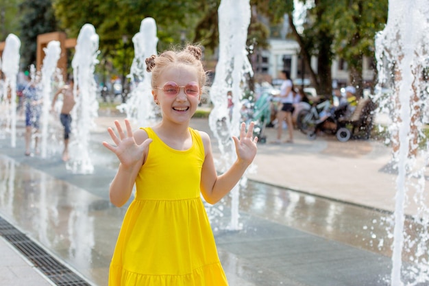 Uma menina feliz corre perto da fonte no verão no parque