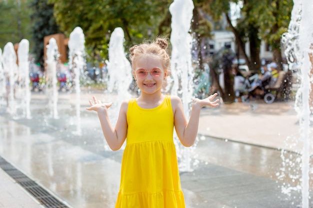 Uma menina feliz corre perto da fonte no verão no parque