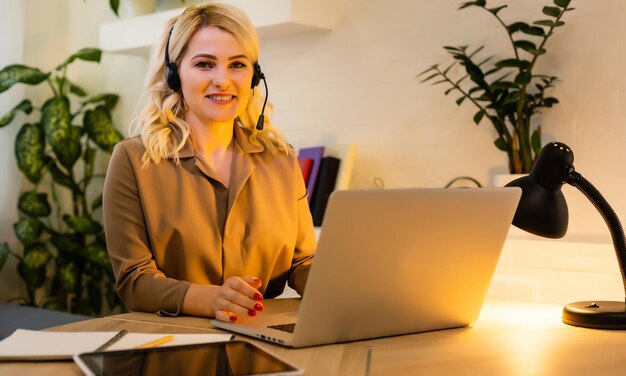 Uma menina feliz trabalha remotamente de casa e se comunica por videochamada com amigos e parentes em seu escritório. Ensino à distância e trabalho online. Usando o computador.