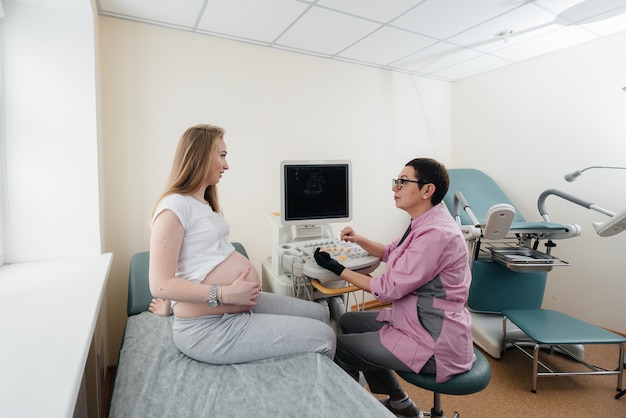 Foto uma menina grávida é aconselhada por um médico após um ultra-som na clínica.