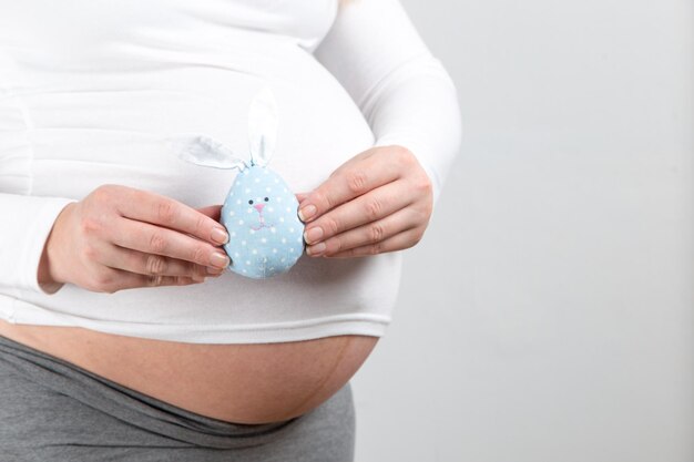 Uma menina grávida segura um brinquedo um coelhinho da páscoa o conceito de gravidez na primavera