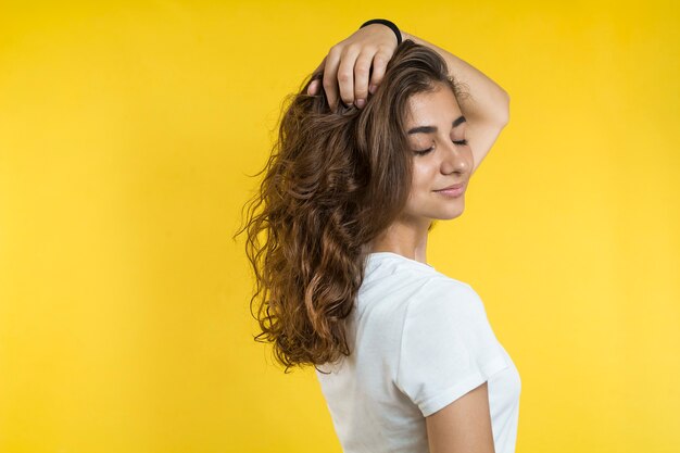 Foto uma menina indiana feliz com cabelo bonito relaxa. morena bonita em um fundo amarelo.