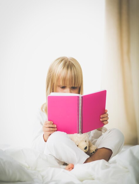 Uma menina lendo um livro com uma capa rosa