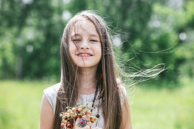 Uma menina linda e feliz na natureza com os morangos no estilo hippie. Dia de sol