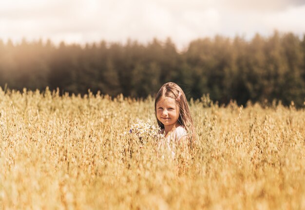 Uma menina loira caminha por um campo dourado no verão. Conceito de pureza, crescimento, felicidade