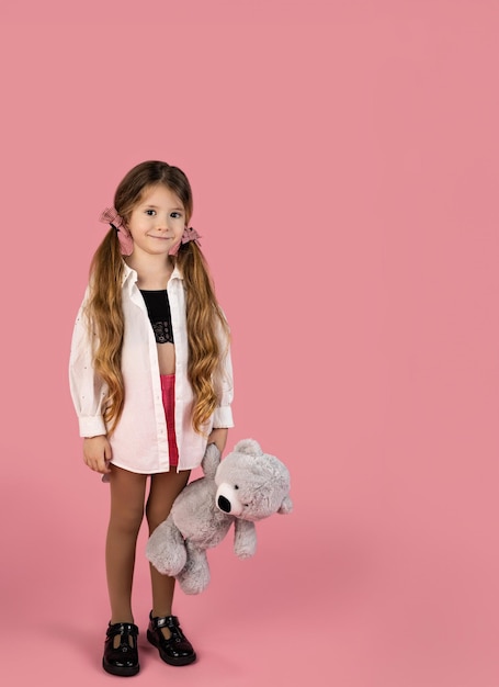Uma menina loira com duas colas segurando seu ursinho de pelúcia cinza retrato de comprimento completo valentines