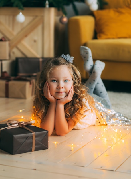 Foto uma menina loira está deitada no chão ao lado de uma árvore e presentes