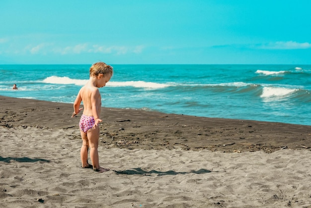 Foto uma menina loira na praia.