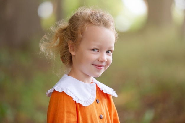 uma menina loira pré-escolar em uma coroa de rowan e com brinquedos caminha no parque em uma manhã de verão