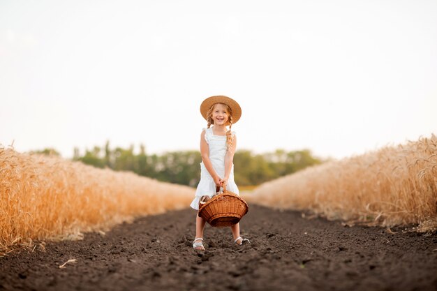 Uma menina loira segurando uma cesta de pão em um campo de trigo