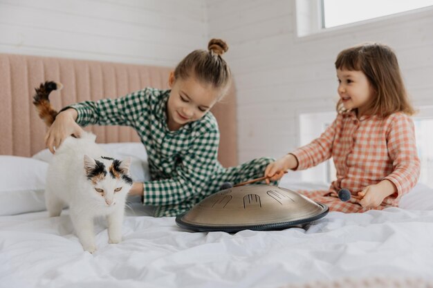 Uma menina loira vestindo pijama abraça um gato doméstico em seu quarto o conceito de uma manhã aconchegante em casa