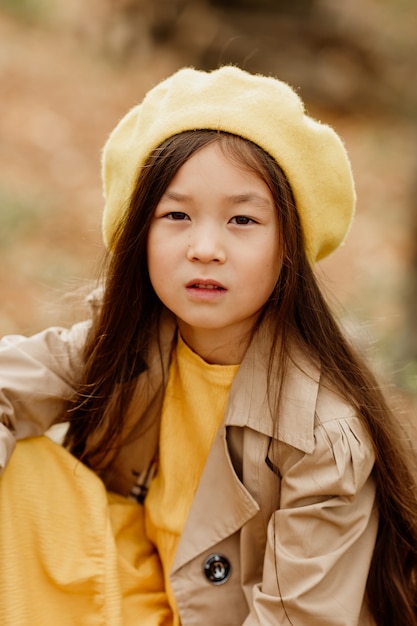 Foto uma menina morena asiática com roupas de outono caminha na floresta de outono perto de um riacho