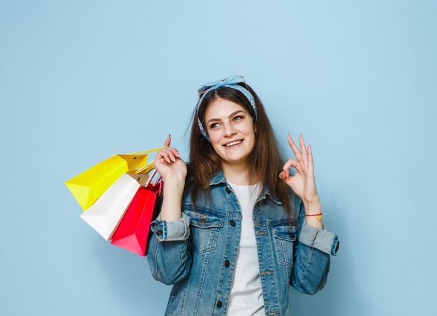 Uma menina morena feliz que foi às compras e mostrando gestos sobre um fundo azul